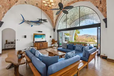 a living room with blue couches and a large window at Dreamy Spanish-Style Villa with Sweeping Ocean Views, Elegant Nautical Design & Giant Infinity Pool in Playa Flamingo