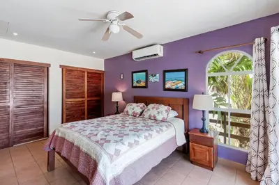 a bedroom with a bed and a purple wall at Charming Duplex in Playa Potrero Surfside Community, with a Private Pool, Cozy Interior and Walkable Access to the Beach in Potrero