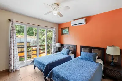 two beds in a bedroom with orange walls and a window at Charming Duplex in Playa Potrero Surfside Community, with a Private Pool, Cozy Interior and Walkable Access to the Beach in Potrero