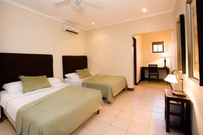 a hotel room with two beds and a table at Beautiful Condo in Peaceful Cliffside Location with a Private Balcony & Stunning Ocean and Mountain Views in Playa Flamingo