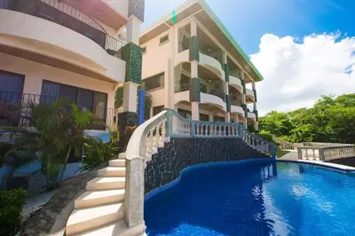 a house with a swimming pool in front of it at Beautiful Condo in Peaceful Cliffside Location with a Private Balcony & Stunning Ocean and Mountain Views in Playa Flamingo
