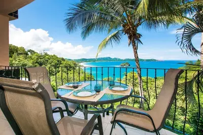 a table and chairs on a balcony with a view of the ocean at Beautiful Condo in Peaceful Cliffside Location with a Private Balcony & Stunning Ocean and Mountain Views in Playa Flamingo