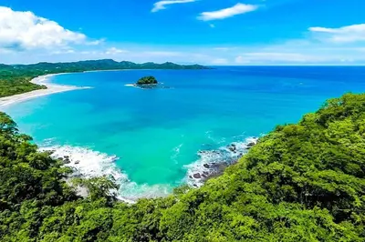 an island in the middle of a body of water at Beautiful Condo in Peaceful Cliffside Location with a Private Balcony & Stunning Ocean and Mountain Views in Playa Flamingo
