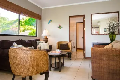 a living room with a couch and a table and chairs at Beautiful Condo in Peaceful Cliffside Location with a Private Balcony & Stunning Ocean and Mountain Views in Playa Flamingo