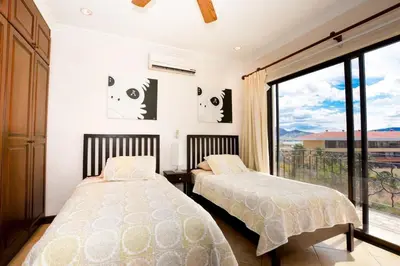 two beds in a bedroom with a large window at Fifth-Floor Condo with Breathtaking Ocean Views, Stylish Interior & Prime Location Near Flamingo Beach in Playa Flamingo