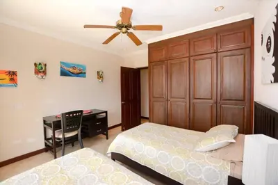 a bedroom with a bed and a desk and a ceiling fan at Fifth-Floor Condo with Breathtaking Ocean Views, Stylish Interior & Prime Location Near Flamingo Beach in Playa Flamingo