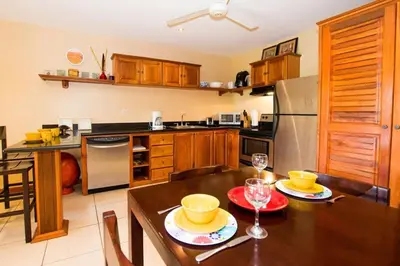 a kitchen with a wooden table and a dining room at Cozy Ground-Floor Condo with Community Pool, Rancho and Lush Garden Views in Brasilito