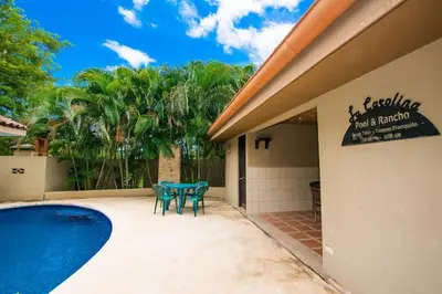 a patio with a table and chairs next to a swimming pool at Cozy Ground-Floor Condo with Community Pool, Rancho and Lush Garden Views in Brasilito