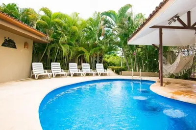 a swimming pool with chairs and an umbrella at Cozy Garden Condo with Vibrant Tropical Decor, Swimming Pool and Rancho in Brasilito