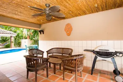 a grill in a kitchen with chairs and a pool at Cozy Garden Condo with Vibrant Tropical Decor, Swimming Pool and Rancho in Brasilito