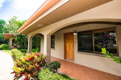 a house with a brown door and some flowers at Cozy Garden Condo with Vibrant Tropical Decor, Swimming Pool and Rancho in Brasilito