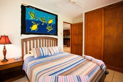 a bedroom with a bed and a tv on the wall at Cozy Garden Condo with Vibrant Tropical Decor, Swimming Pool and Rancho in Brasilito