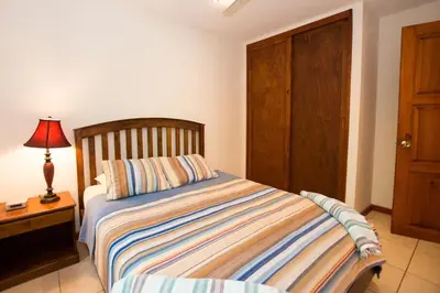 a bedroom with a bed and a lamp on a table at Cozy Garden Condo with Vibrant Tropical Decor, Swimming Pool and Rancho in Brasilito