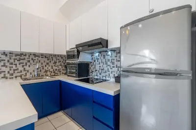 a kitchen with blue cabinets and a refrigerator at Top-Floor Condo with Sweeping Ocean, Mountain & Marina Views in Playa Flamingo