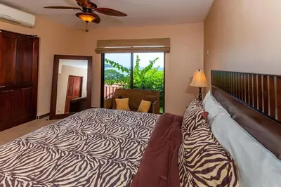 a bedroom with a zebra print bed with a ceiling fan at Big Hillside Villa in Potrero with Pool and Panoramic Ocean Views in Potrero