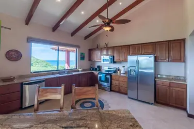 a kitchen with wooden cabinets and stainless steel appliances at Big Hillside Villa in Potrero with Pool and Panoramic Ocean Views in Potrero