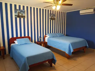 a bedroom with two beds and a ceiling fan at Hotel Grosseto Palma Real in Loma