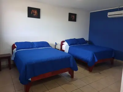 two beds in a room with blue sheets at Hotel Grosseto Palma Real in Loma