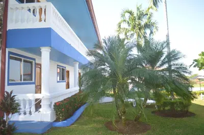 a house with palm trees in front of it at Hotel Grosseto Palma Real in Loma