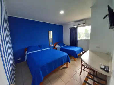 a blue bedroom with two beds and a desk at Hotel Grosseto Palma Real in Loma