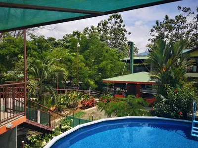 a swimming pool in front of a building with trees at Hotel Cabinas el Tecal in Uvita