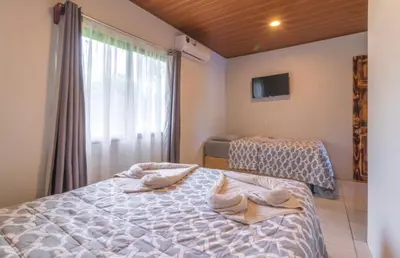 a bedroom with two beds and a large window at Hotel Cabinas el Tecal in Uvita