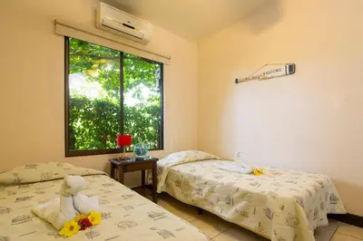two beds in a room with a window at Playa Potrero Apartments in Potrero