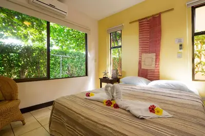 a bedroom with two beds with towels and windows at Playa Potrero Apartments in Potrero