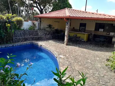 a swimming pool in front of a house at Dos Palmas Studio Apartments in Alajuela City
