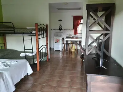 a room with two bunk beds and a kitchen at Dos Palmas Studio Apartments in Alajuela City