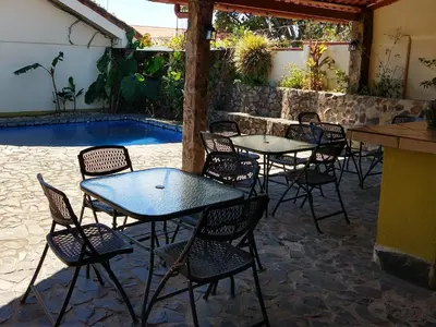 a group of tables and chairs next to a pool at Dos Palmas Studio Apartments in Alajuela City