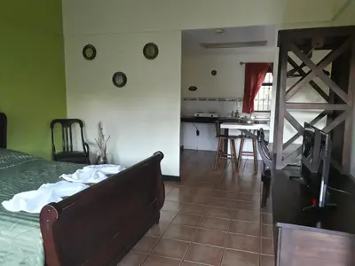 a bedroom with a bed and a kitchen with a table at Dos Palmas Studio Apartments in Alajuela City