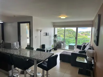 a living room with a table and a couch at Charming Two Bedroom with balcony in San José