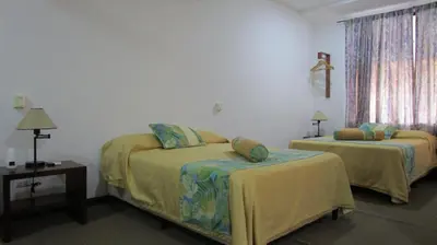 a bedroom with two beds and a table and a window at Sueño Tranquilo in Quepos