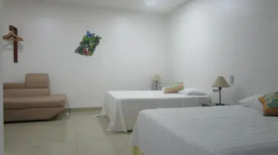 a hotel room with two beds and a chair at Sueño Tranquilo in Quepos