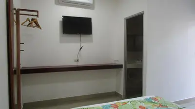 a bedroom with a tv on the wall and a bed at Sueño Tranquilo in Quepos