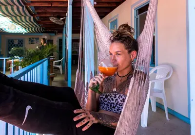 a woman sitting in a hammock with a glass of wine at Hostel Samara in Sámara