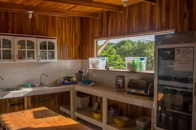 a kitchen with a counter with a sink and a refrigerator at Hostel Samara in Sámara