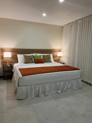 a bedroom with a large bed with two lamps at Hotel Iguana Verde in Orotina
