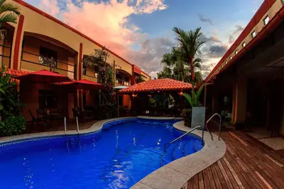 a swimming pool in front of a building at Hotel Iguana Verde in Orotina