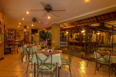 a restaurant with tables and chairs and a ceiling fan at Hotel Iguana Verde in Orotina