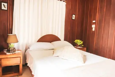 a bedroom with a bed with white sheets and pillows at Cabinas Lupita in Fortuna