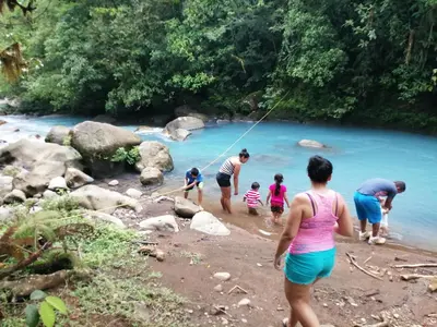 a group of people playing in the water at a river at Cabinas Piuri in Rio Celeste