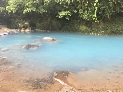 a blue pool of water with rocks in it at Cabinas Piuri in Rio Celeste