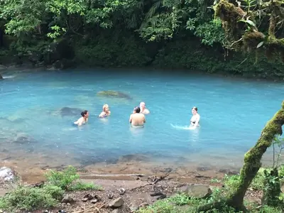 a group of people swimming in a river at Cabinas Piuri in Rio Celeste