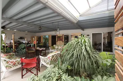 a conservatory with chairs and tables and plants at Casa María Aeropuerto B&B in Alajuela City