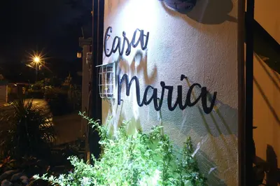 a sign on the side of a building with a plant at Casa María Aeropuerto B&B in Alajuela City