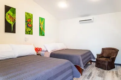 a room with two beds and a chair at Casa María Aeropuerto B&B in Alajuela City