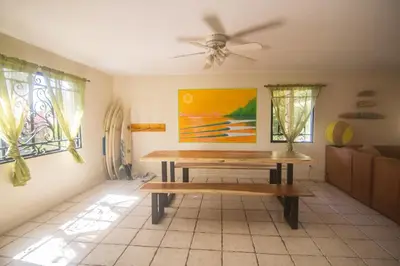a room with a wooden bench in a room with windows at Wipeout Guest House in Jacó