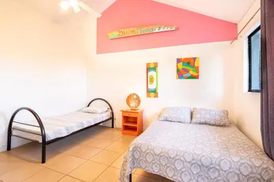 a bedroom with two beds and a sign on the wall at Wipeout Guest House in Jacó